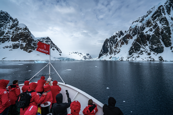 Cruise guests wearing red jackets gathered at tip of SilverSeas ship on Antarctica Cruise on King George Island