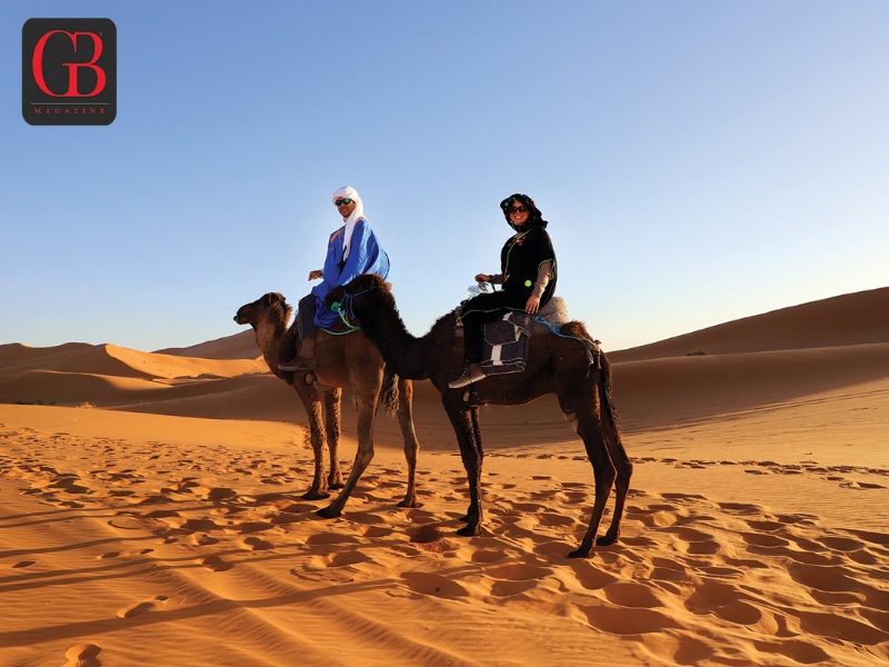 Esteban and Danitza riding camels in the desert in Erg Chebbi, Morocco